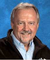 Professional headshot portrait of Sam Todd wearing dark jacket and blue shirt